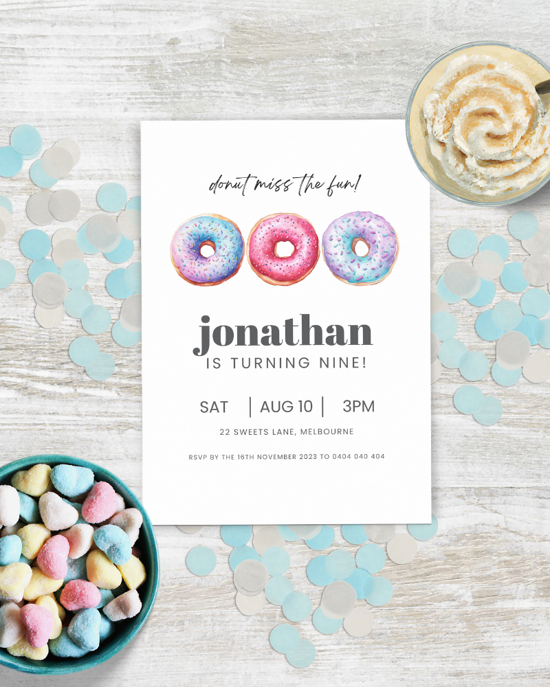 Colorful heart-shaped candies surrounded by confetti on a wooden surface, with a birthday invitation featuring donuts.