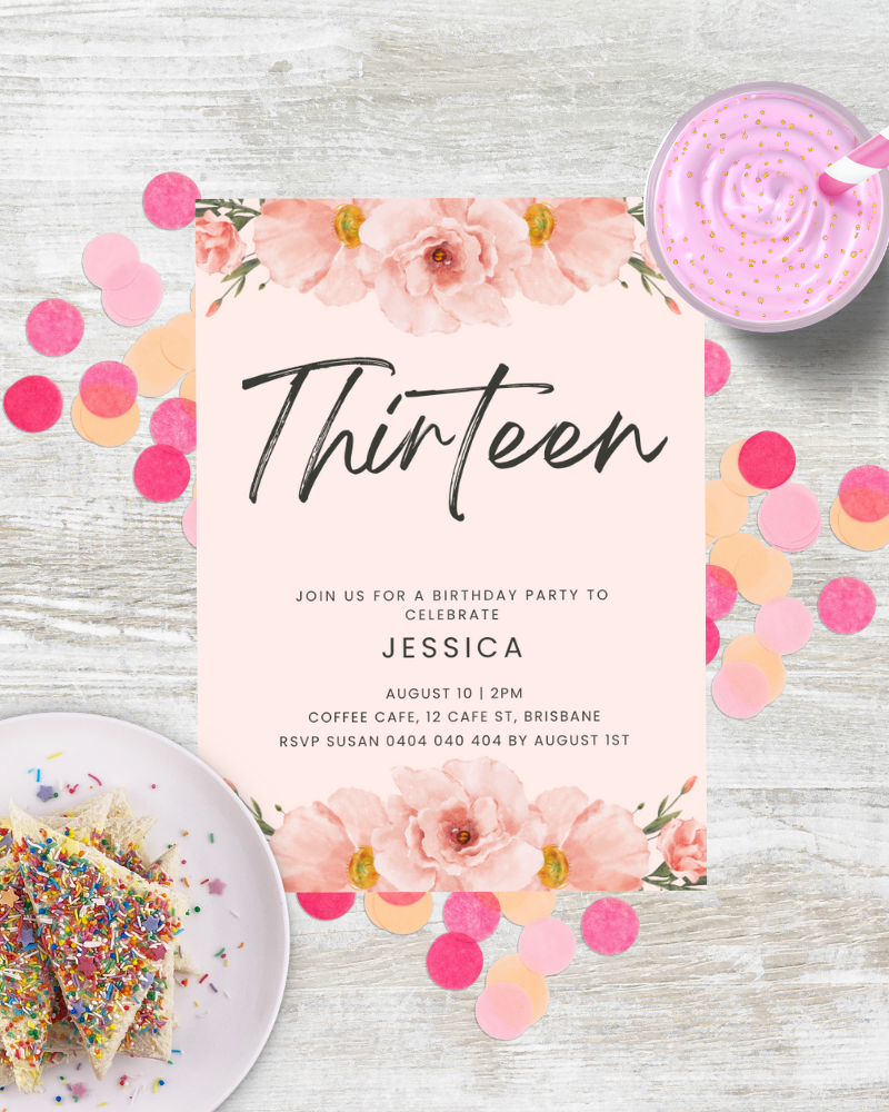 Birthday invitation with floral accents, colorful confetti, and a dessert on a plate, set on a light wooden background.
