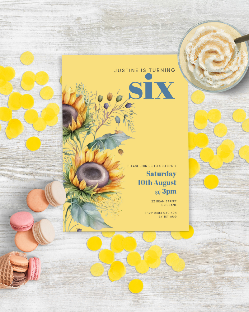Bright invitation featuring sunflowers, colorful confetti, and sweet treats on a rustic wooden surface.