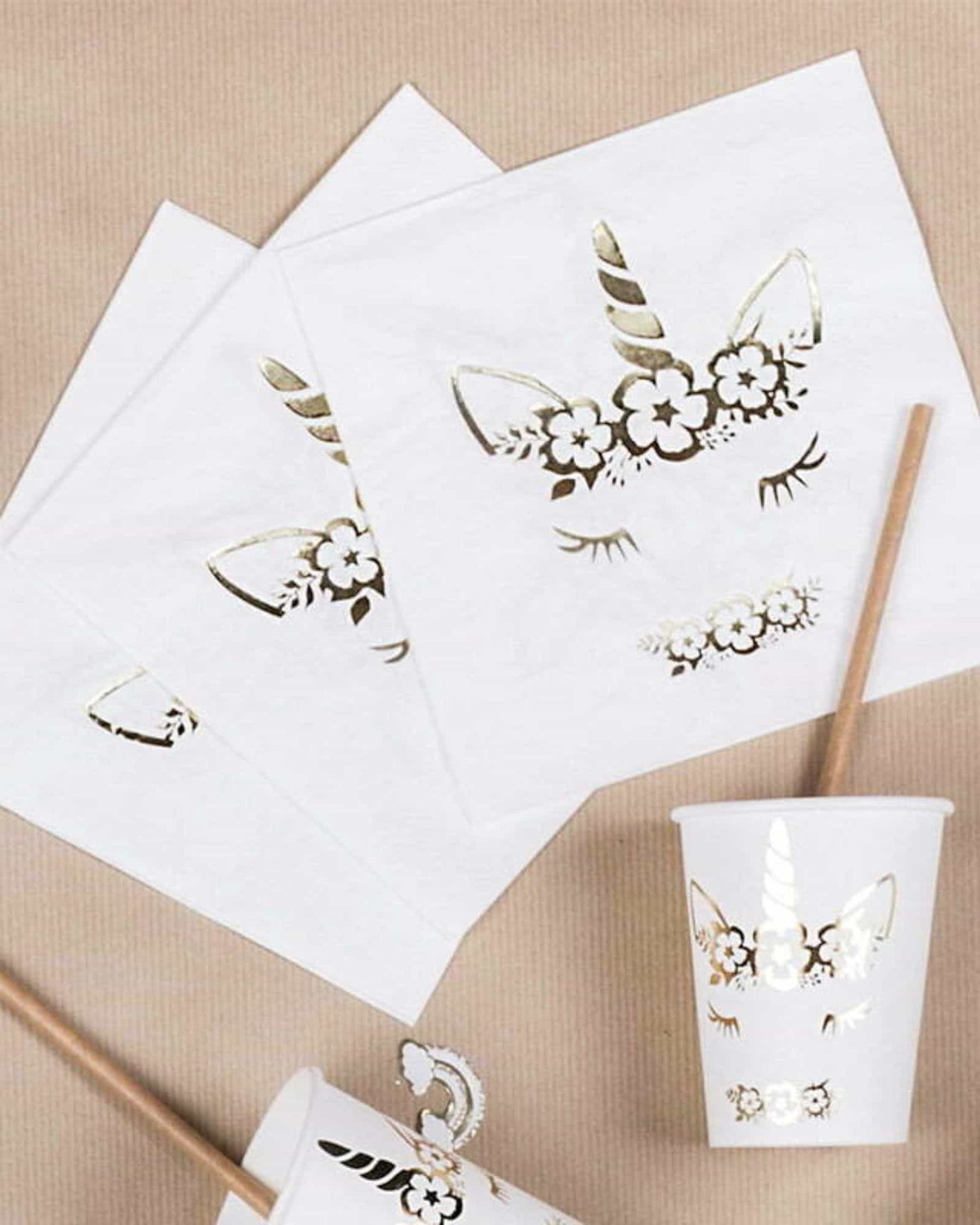 White napkins and a cup featuring a whimsical unicorn face adorned with flowers and a golden horn.