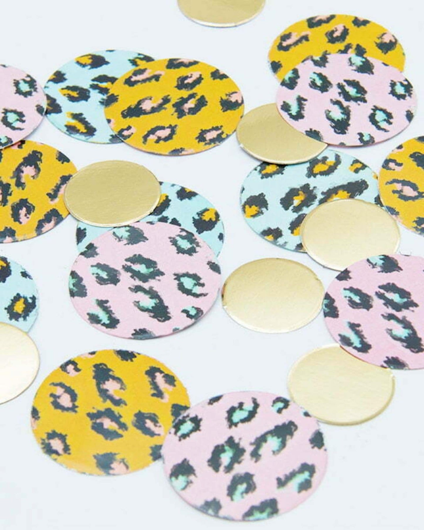Colorful circular pieces in varying patterns and metallic finishes scattered on a light background.