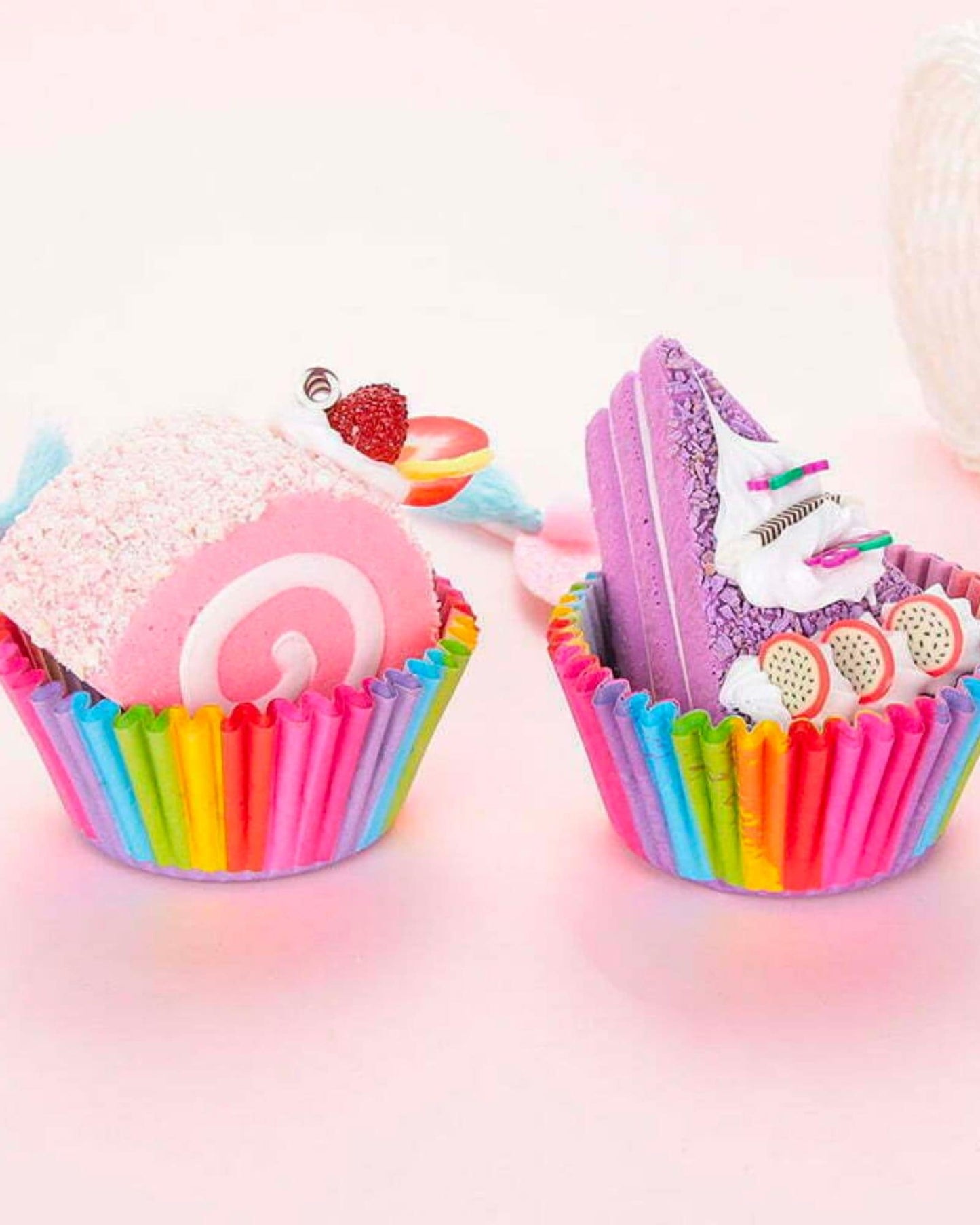 Colorful confections in vibrant wrappers, featuring a pink roll and a purple slice adorned with playful toppings.