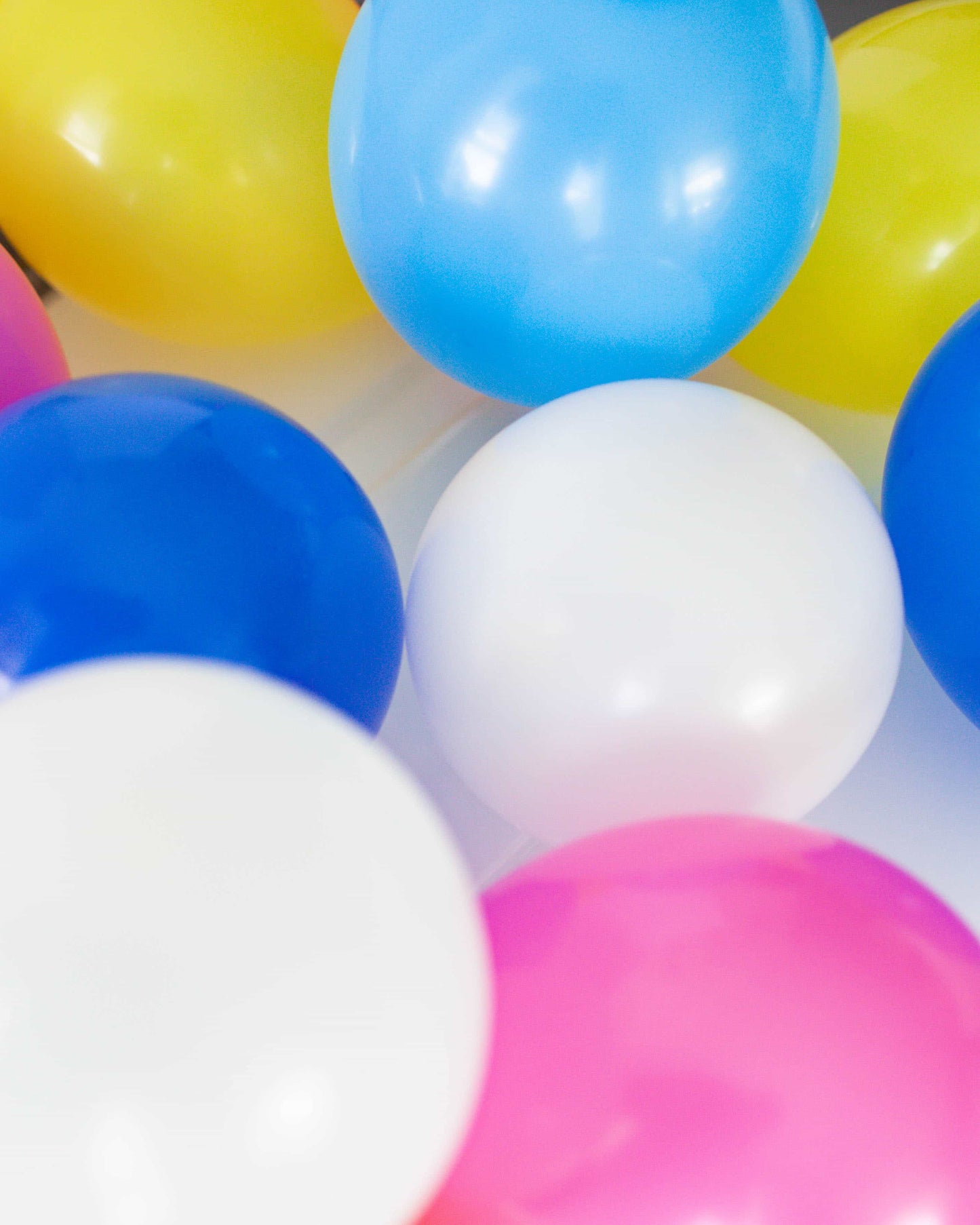Colorful, glossy spheres in pink, blue, yellow, and white clustered together, creating a playful and cheerful atmosphere.