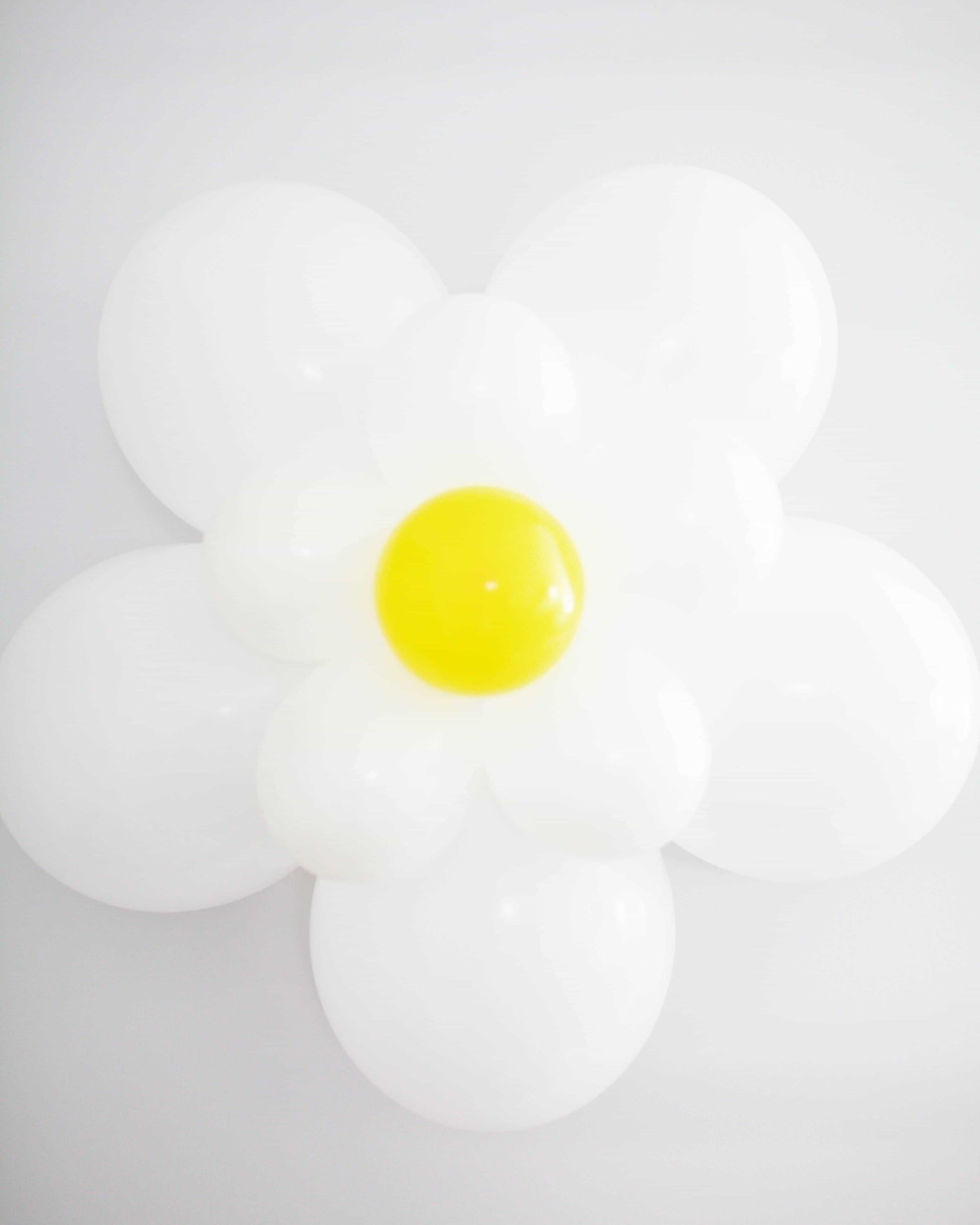 A large, white flower with a bright yellow center against a light background, exuding a playful and cheerful vibe.