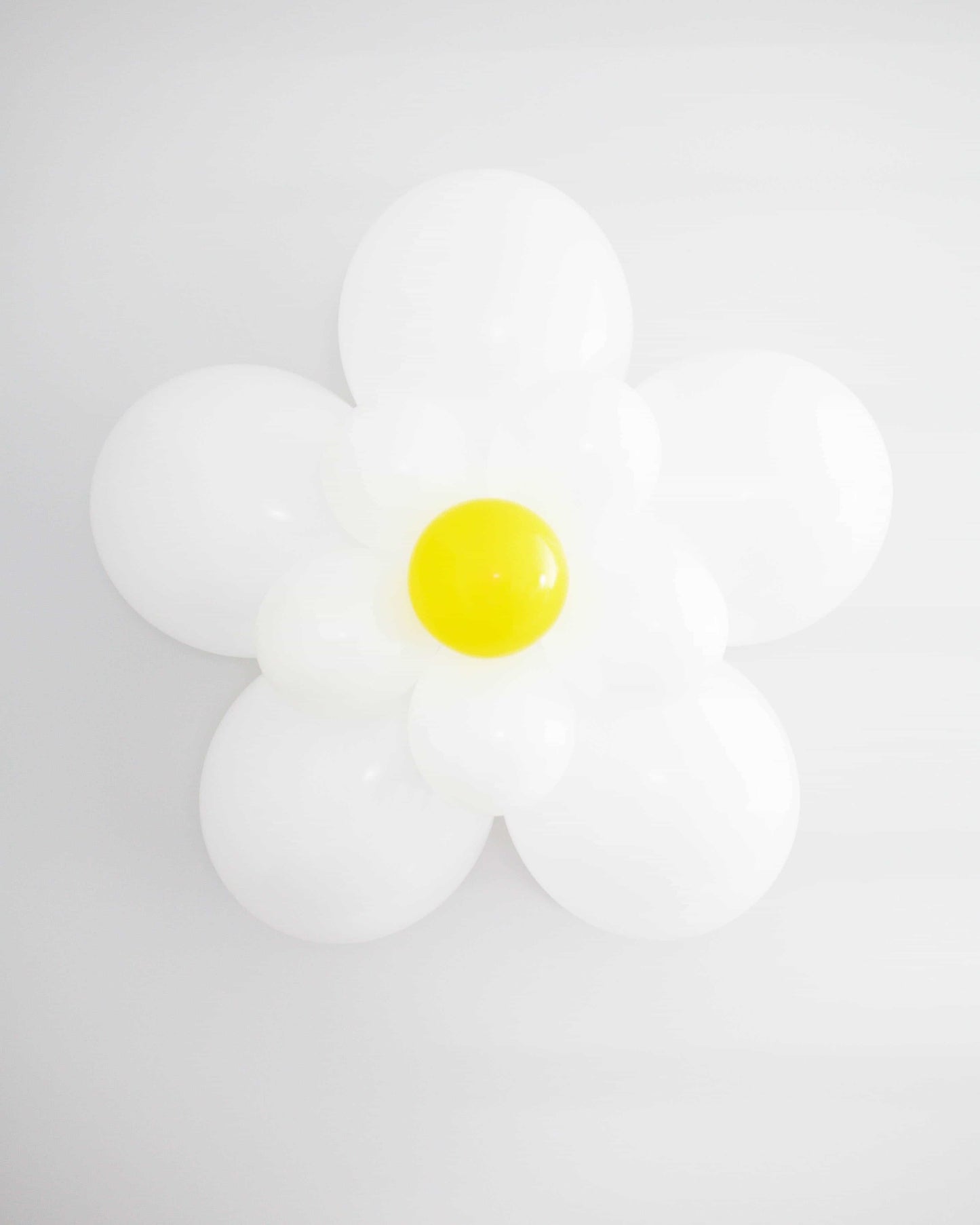 A decorative arrangement resembling a daisy, featuring white and yellow rounded elements against a light background.