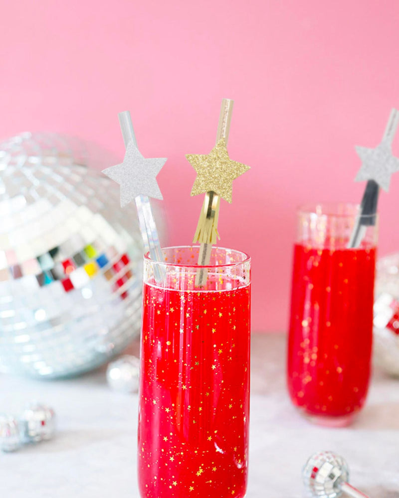 Silver and gold paper straws with decorative matching stars in glass with red drink