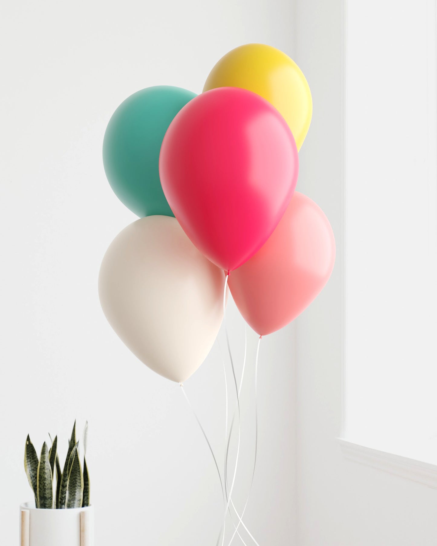 A vibrant bunch of balloons in various colors, including pink, yellow, and teal, against a bright, minimal backdrop.