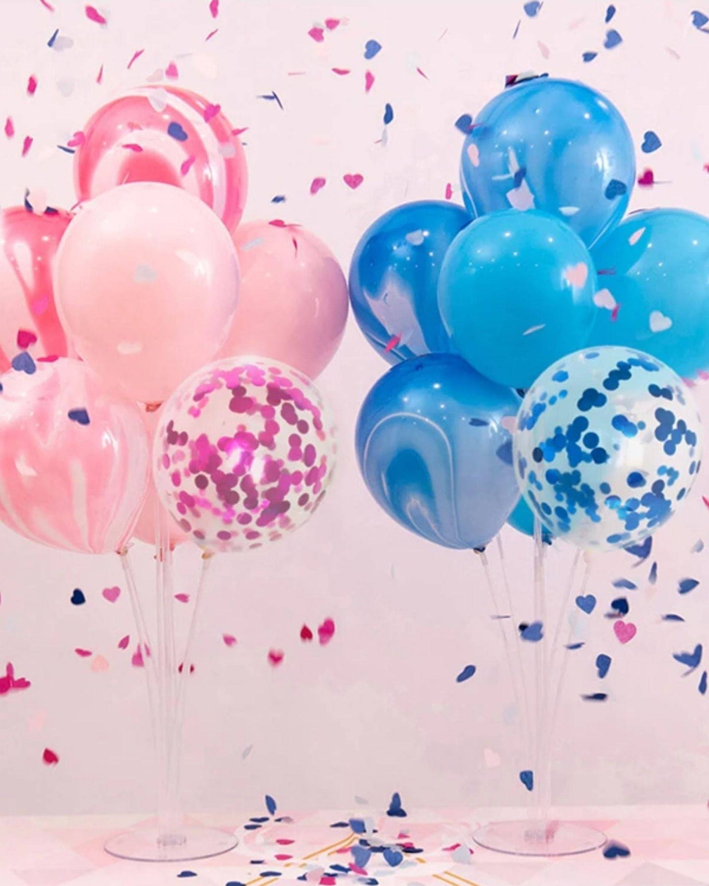 Colorful balloons in pink and blue, with confetti hearts scattered around, creating a festive atmosphere.