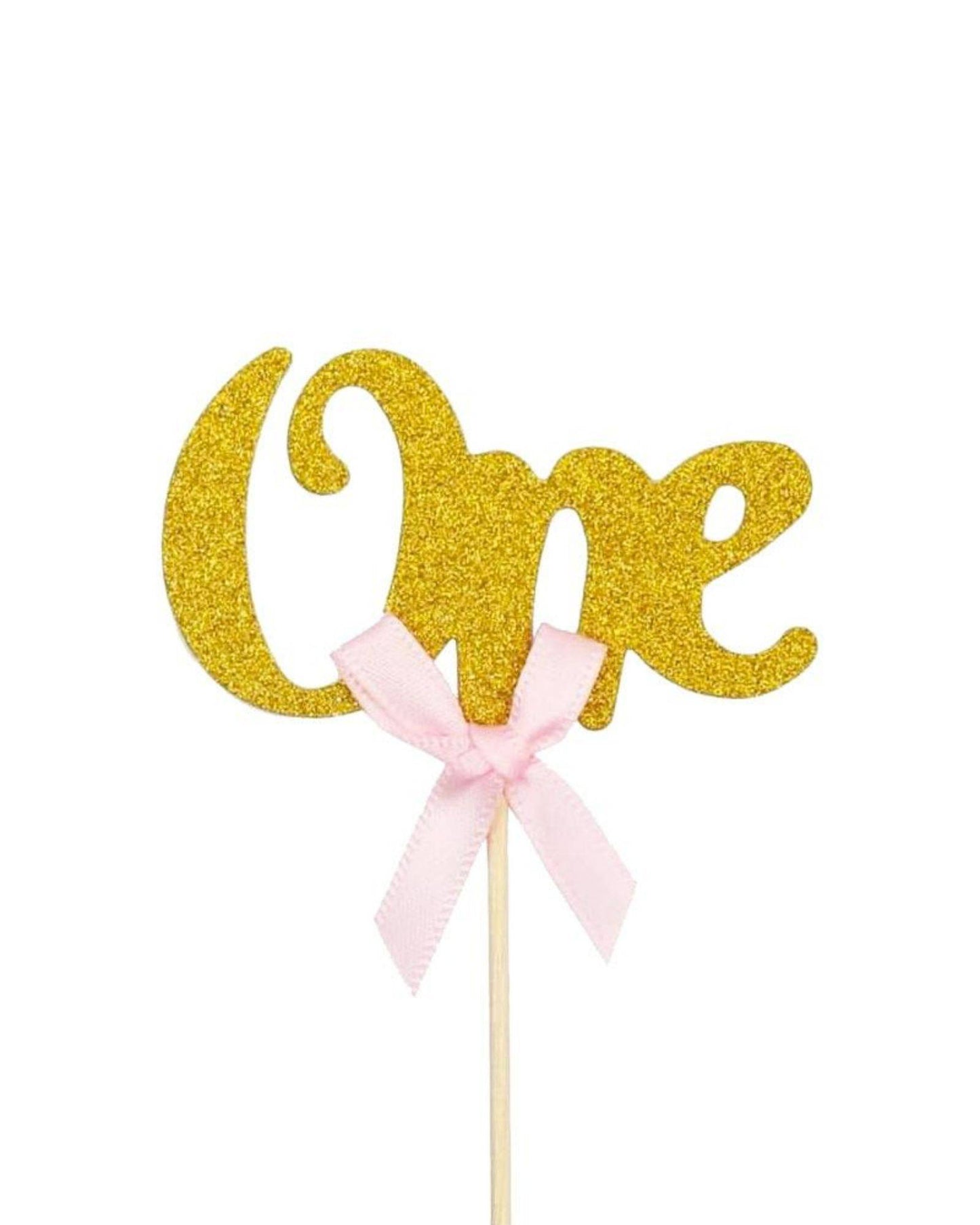 Golden "One" topper adorned with a pink bow, perfect for celebrations or special occasions.