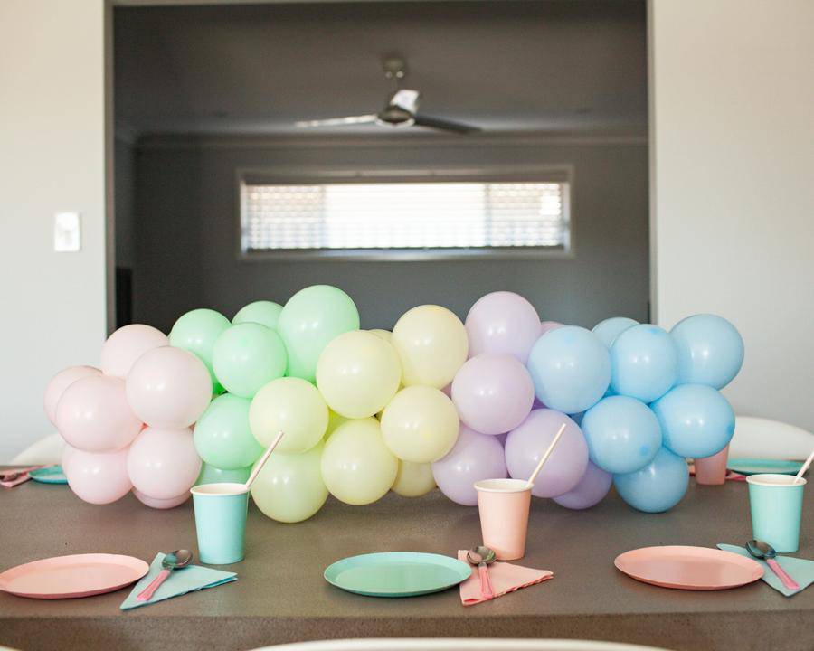 A colorful arrangement of pastel balloons and party cups on a table, creating a festive atmosphere for celebration.