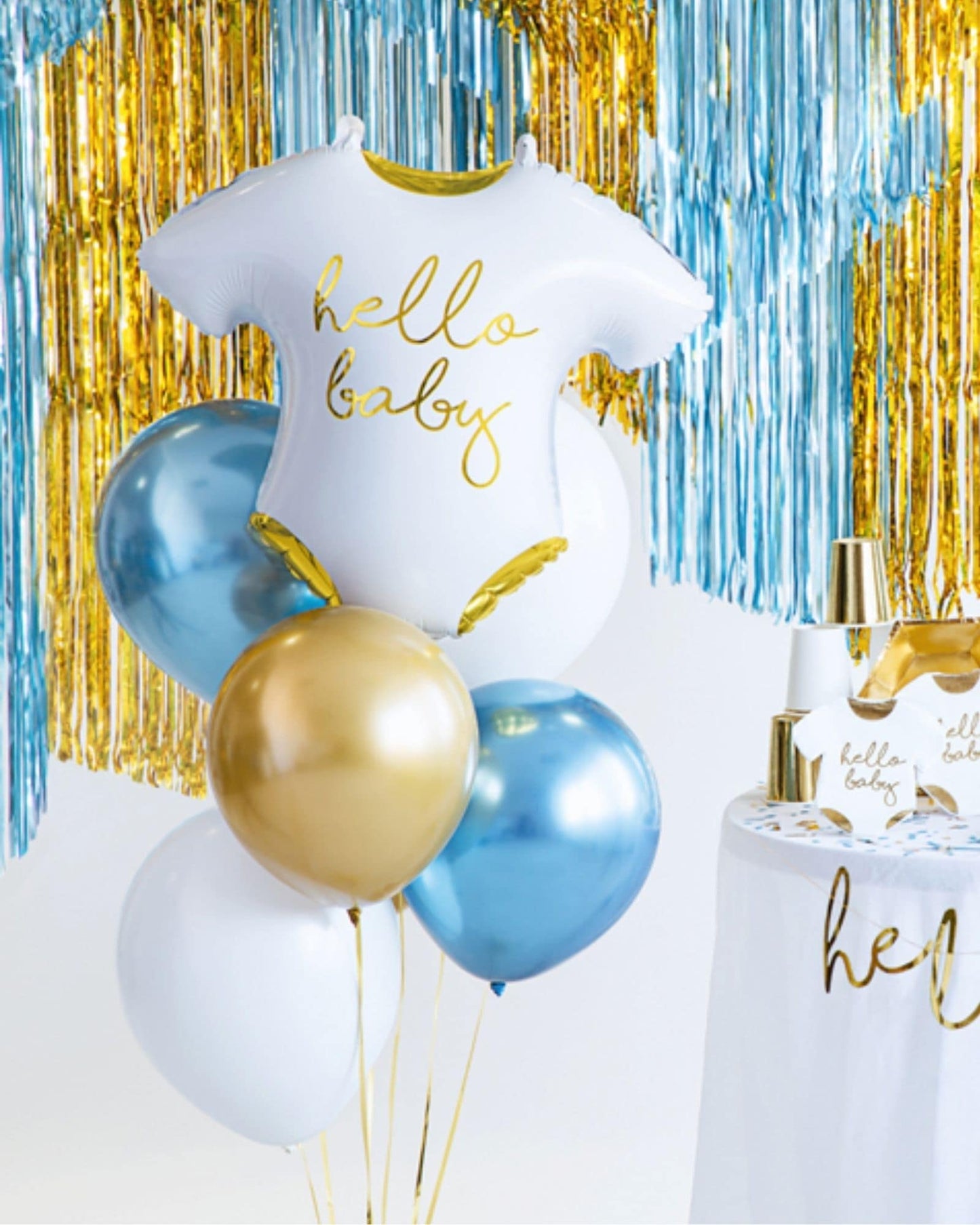 White balloon shaped like a baby onesie with "hello baby" text, surrounded by blue and gold balloons and shiny streamers.