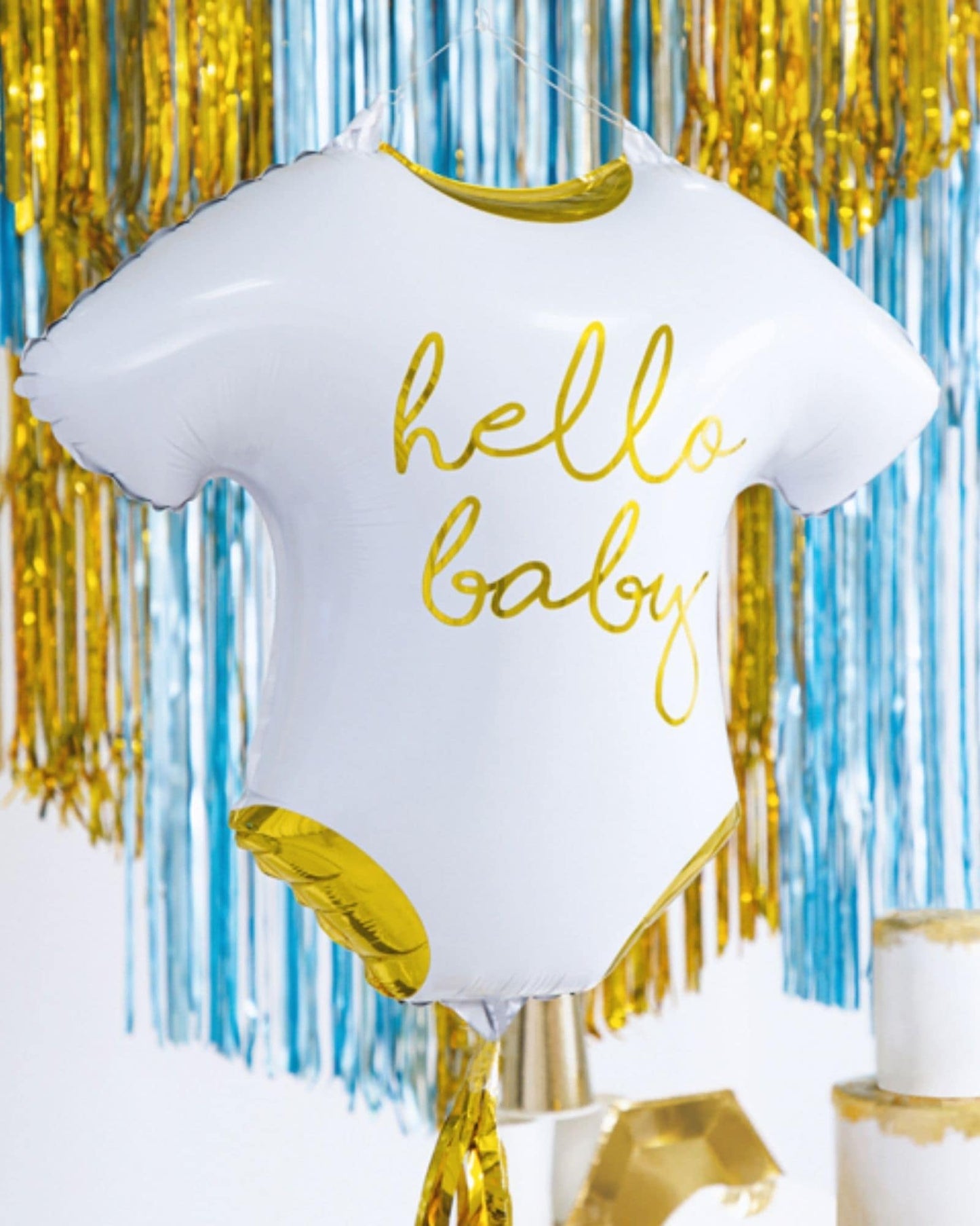 A white balloon shaped like a onesie with "hello baby" in gold, surrounded by colorful streamers.