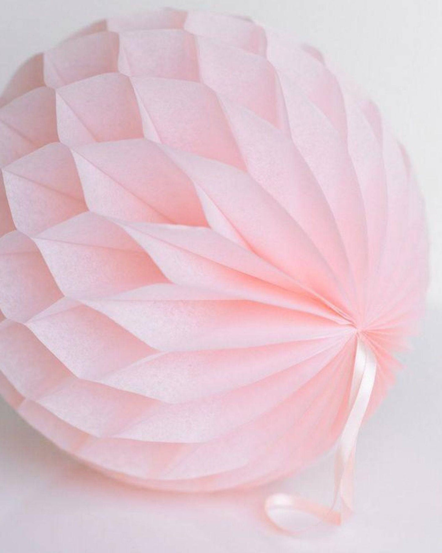 Delicate pink honeycomb decoration with a textured surface and a soft ribbon accent.