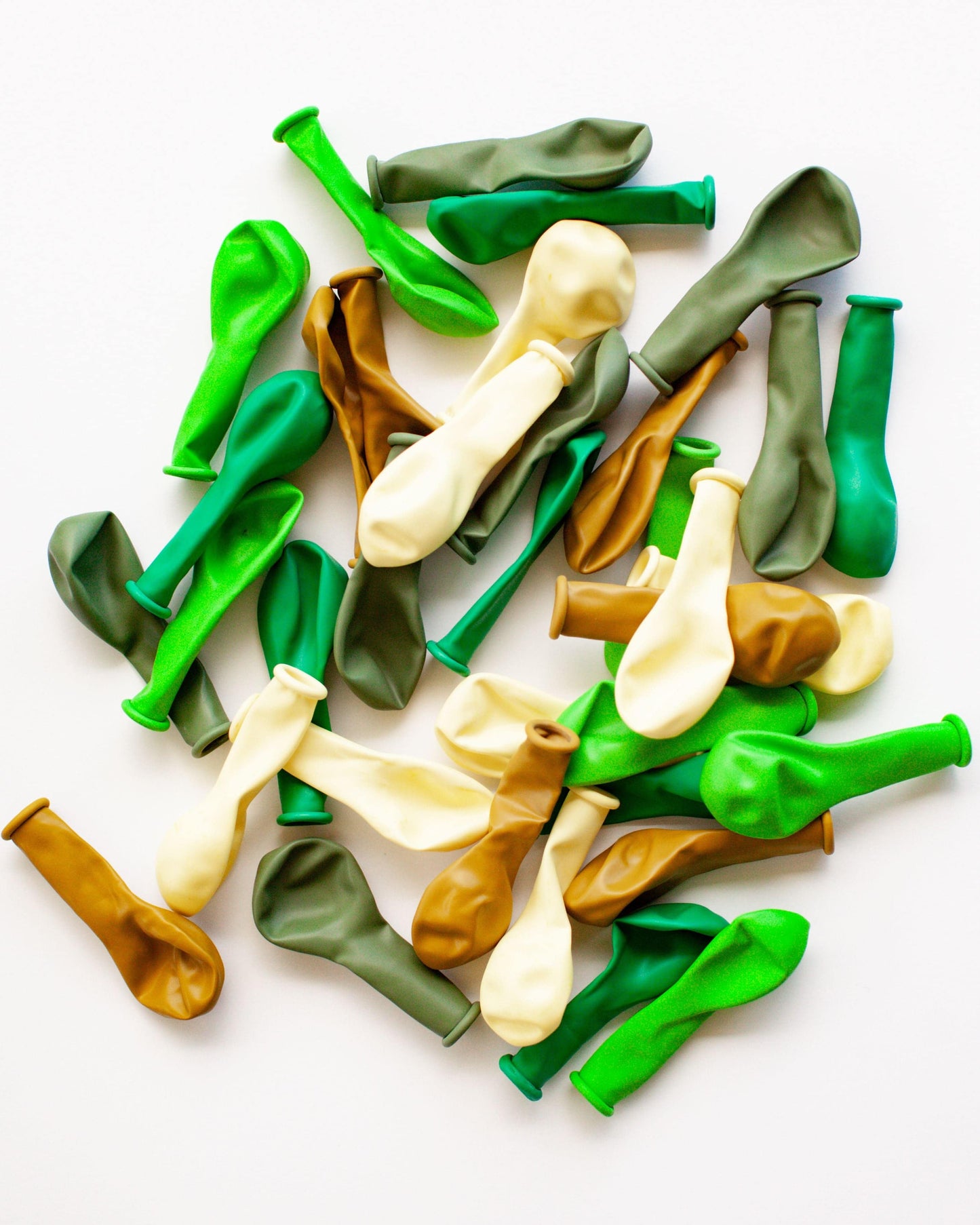 A colorful mix of green, brown, and cream balloons scattered on a white background.