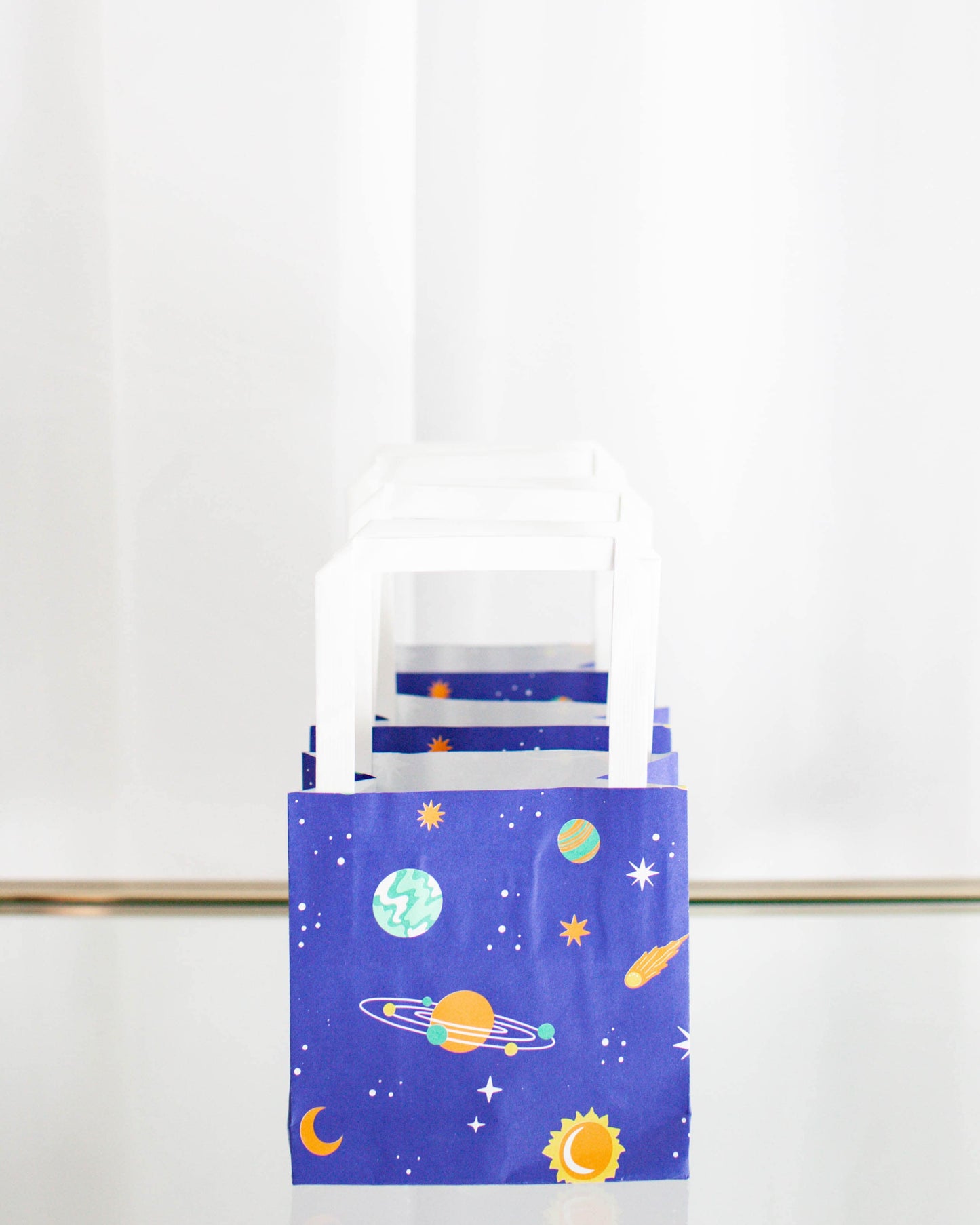 Colorful bags featuring a cosmic theme with planets, stars, and a sun against a deep blue background.