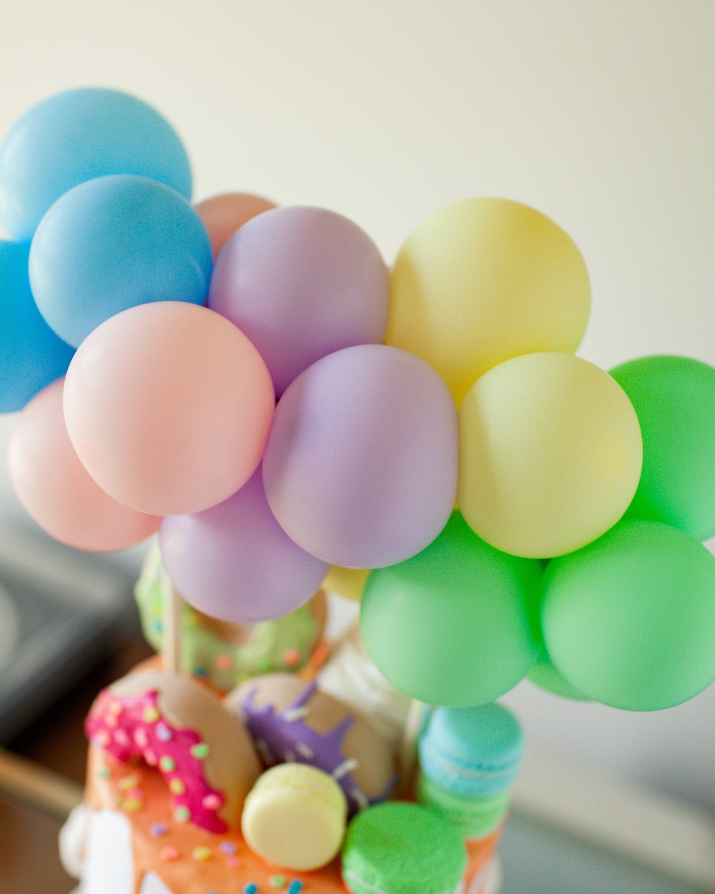 A cluster of pastel balloons in blue, pink, purple, yellow, and green, perched atop a colorful, decorated base.