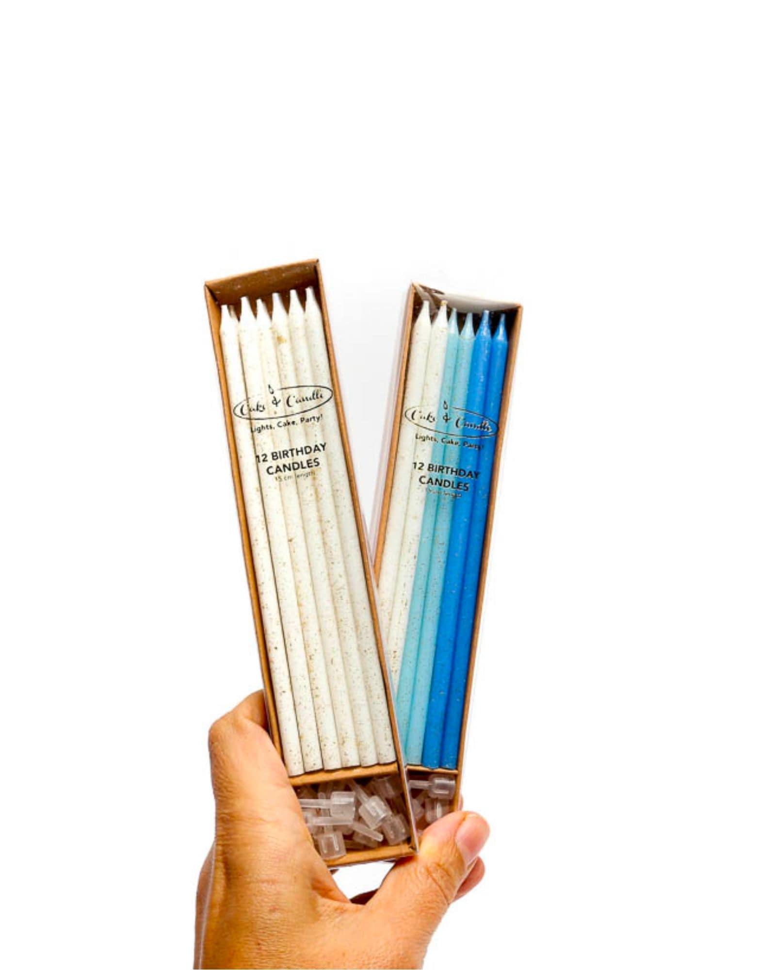 Hand holding a box of birthday candles in white and blue, featuring a speckled texture and clear holders.