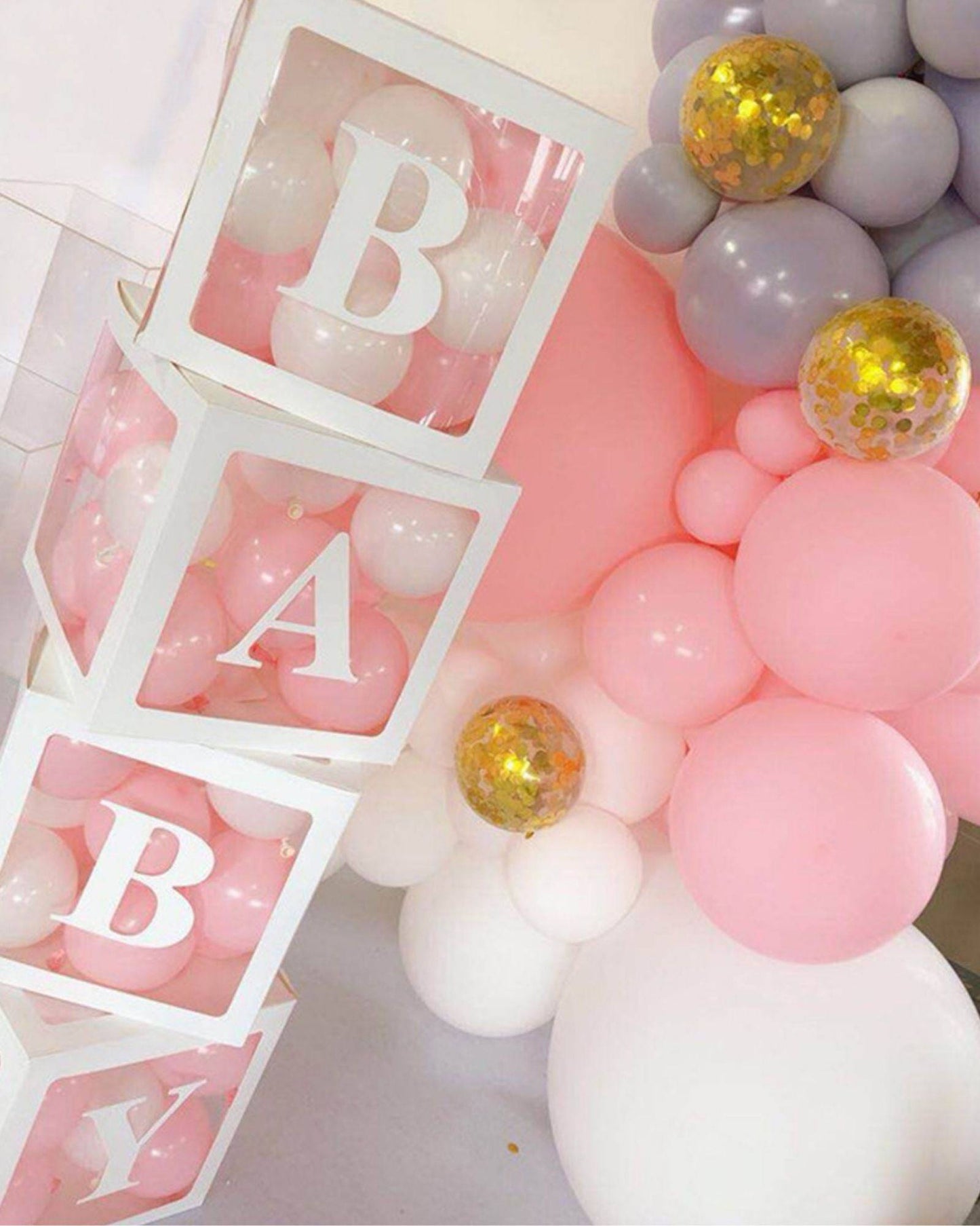 White boxes with letters spelling "BABY" reveal soft pink and white balloons, surrounded by colorful balloon clusters.
