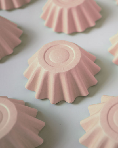 Pink, fluted shapes arranged on a light background, showcasing soft curves and subtle shadows.