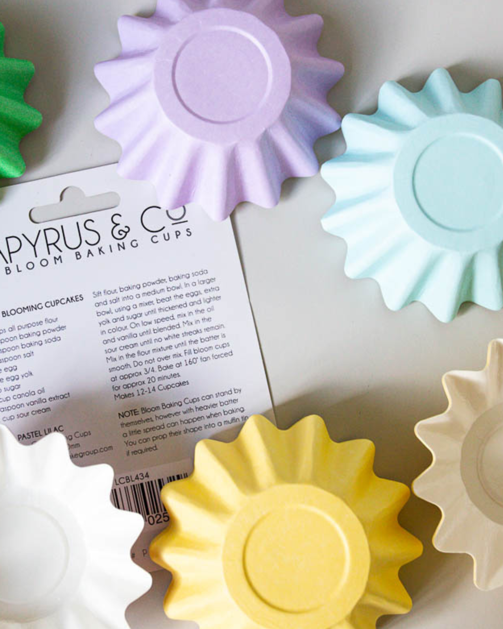 Colorful, fluted baking cups in pastel shades of green, purple, blue, yellow, and cream, displayed with instructions.