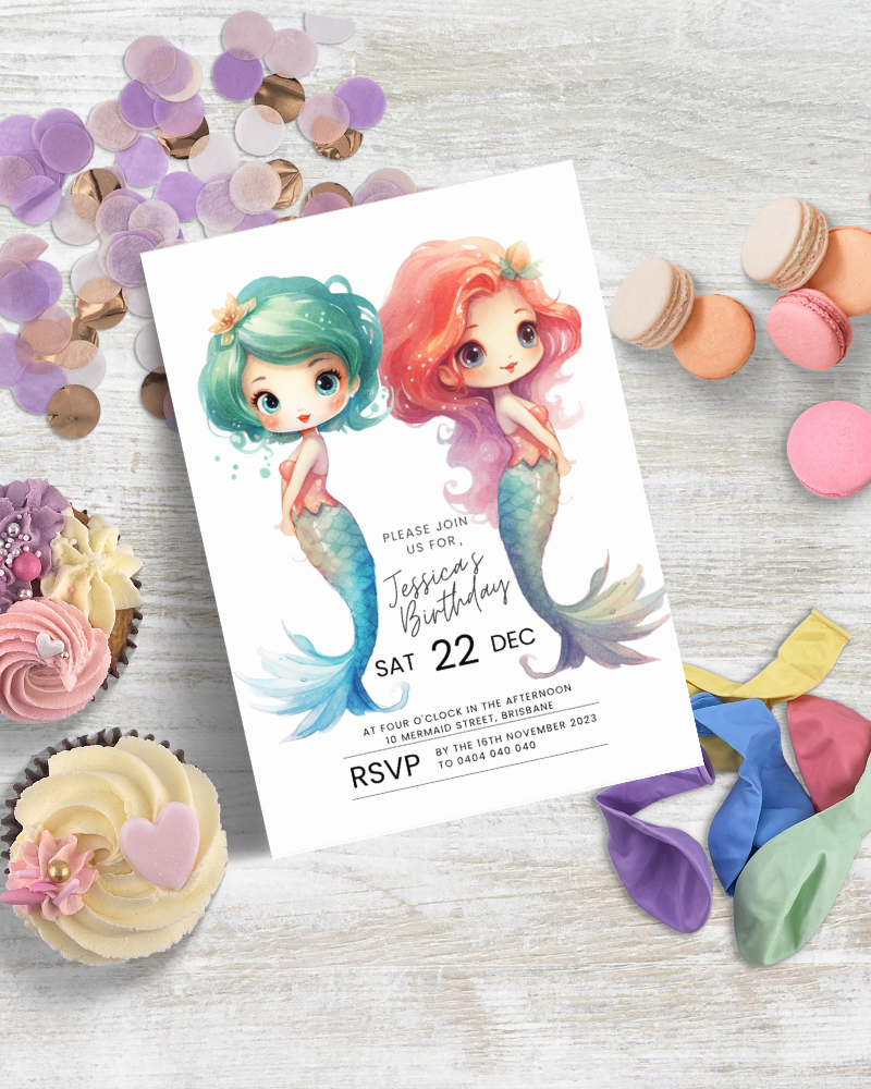 Whimsical invitation featuring two mermaids, colorful balloons, and sweet treats on a light wooden surface.