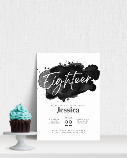 A cupcake with teal frosting beside a black and white invitation for a birthday celebration.