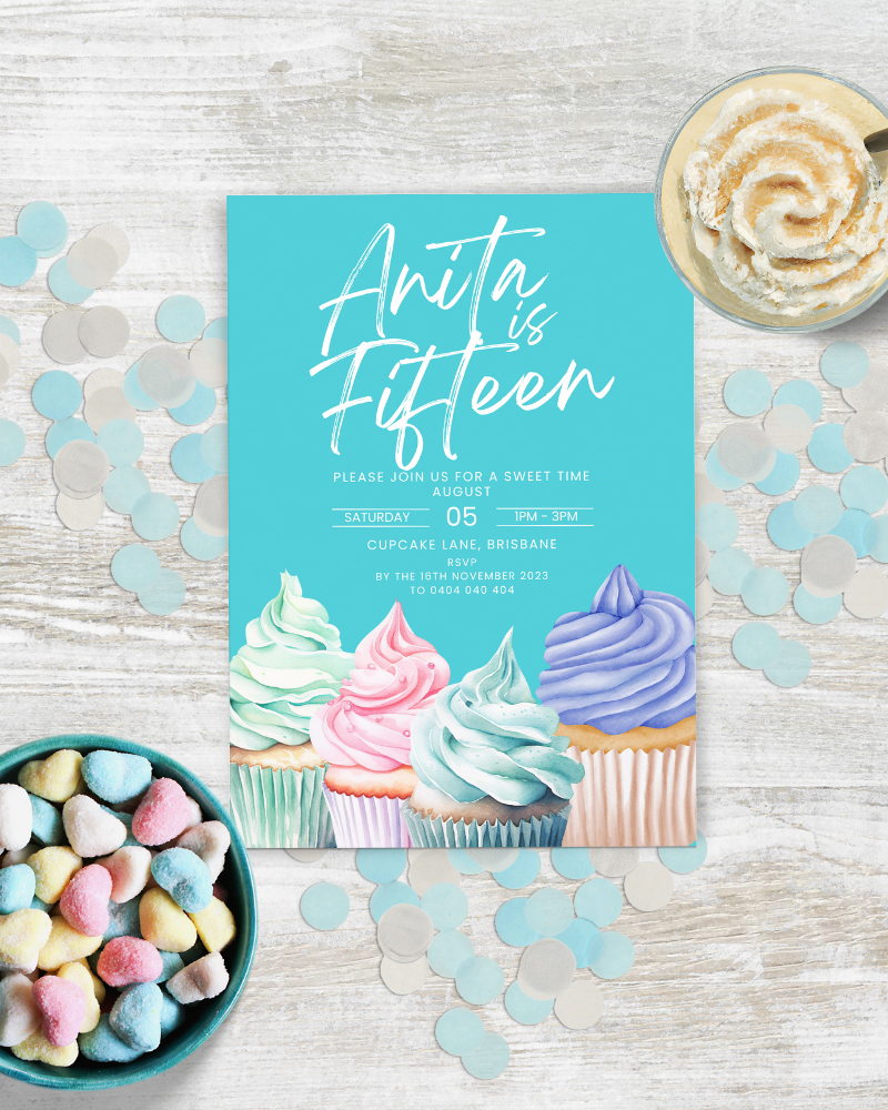 Colorful cupcakes and heart-shaped candies on a wooden table, with a festive invitation for a birthday celebration.