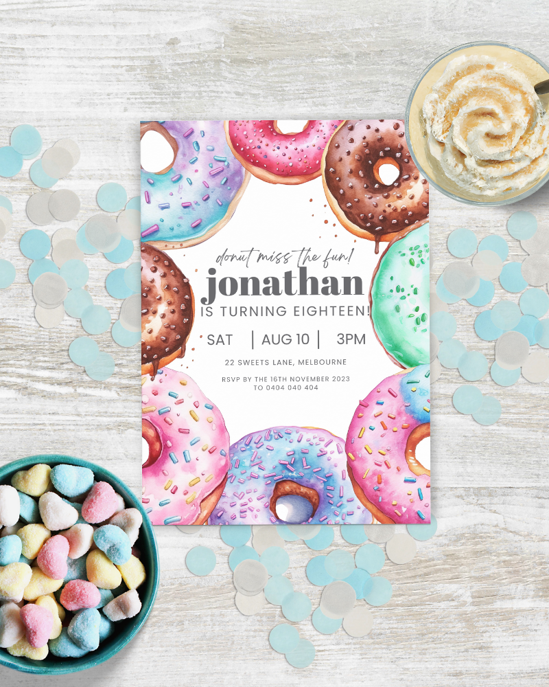 Birthday invitation featuring colorful donuts and pastel confetti on a textured surface with a bowl of heart-shaped candies.