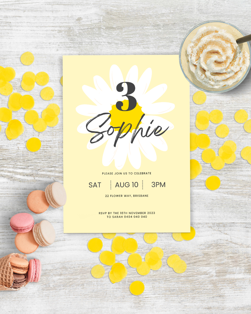 A festive invitation featuring a daisy design, colorful confetti, and sweet treats on a light wooden surface.