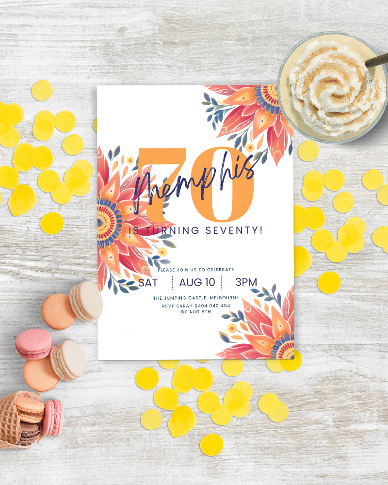 Colorful invitation with floral accents, yellow confetti, macarons, and a creamy dessert on a rustic surface.