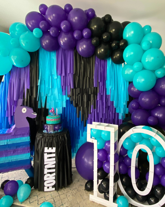 Colorful balloon arch with a festive display featuring a cake and a themed figure celebrating a milestone birthday.