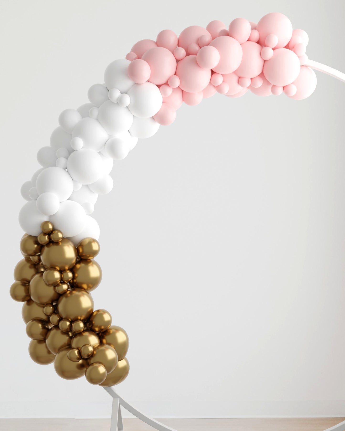 A colorful balloon garland in pink, white, and gold, gracefully arching against a light background.