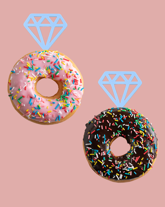 Two colorful donuts with sprinkles, one pink and one chocolate, topped with playful diamond shapes against a pastel backgroun