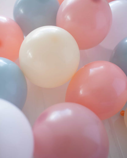 A cluster of pastel-hued balloons in soft pink, blue, and cream, creating a cheerful and festive atmosphere.