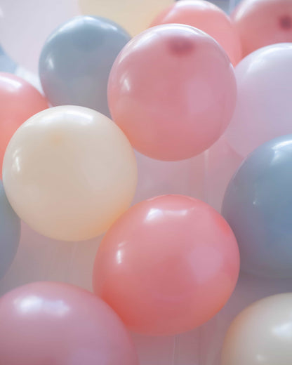 A cluster of pastel-colored balloons in pink, blue, and cream shades, creating a soft, festive atmosphere.