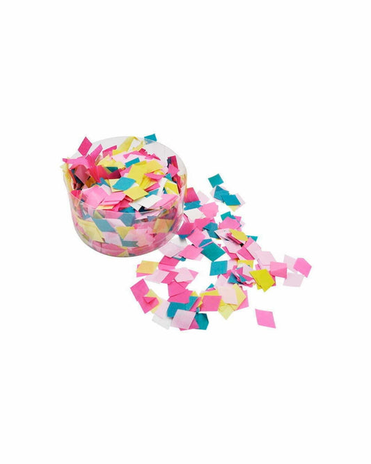 A clear container filled with colorful square cutouts in pink, yellow, and blue, with some scattered around.