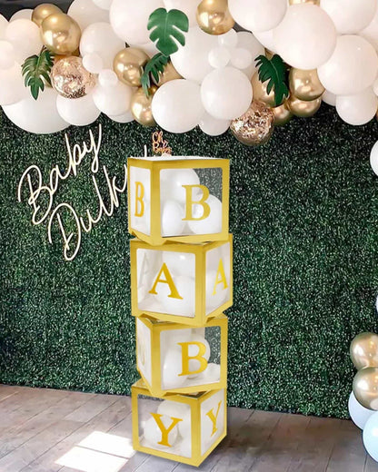 Colorful stacked blocks spell "BABY," surrounded by balloons and greenery, creating a festive atmosphere.