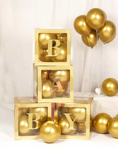 Three golden blocks with letters B, A, and Y, surrounded by shiny gold spheres and a cluster of golden balloons.