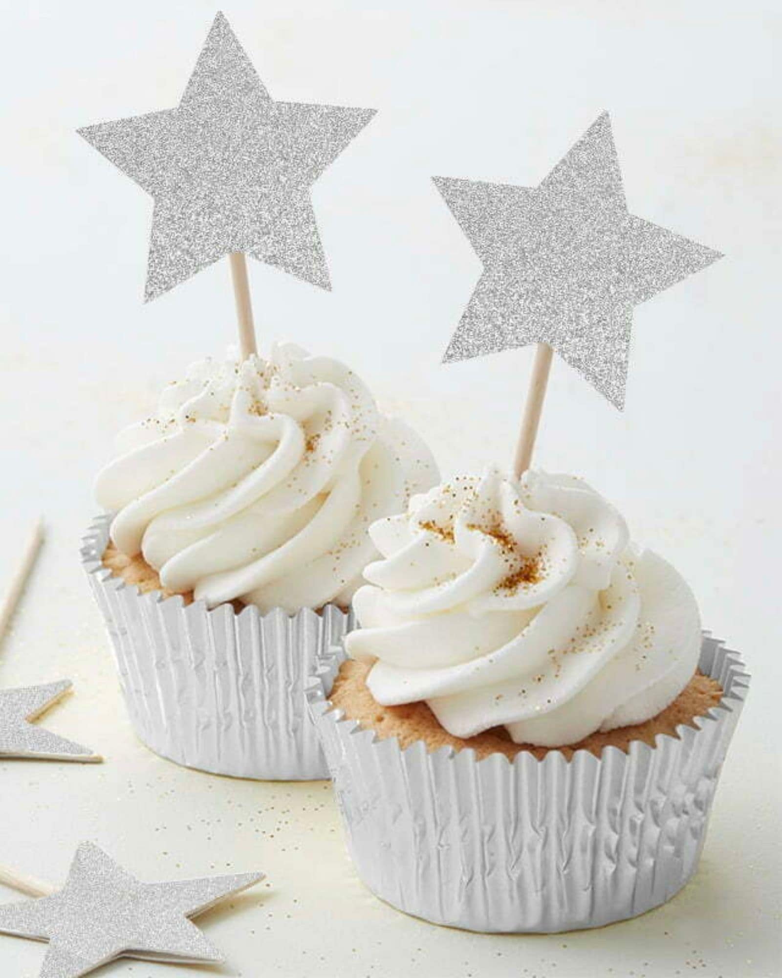 Two frosted treats topped with glittery star picks, surrounded by scattered star shapes on a soft background.