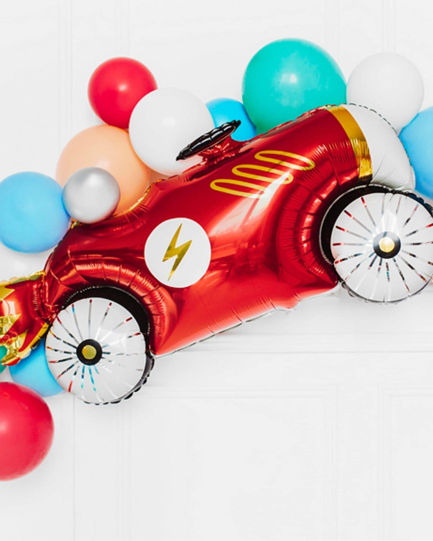 Bright red vehicle-shaped balloon surrounded by colorful balloons in a festive arrangement.