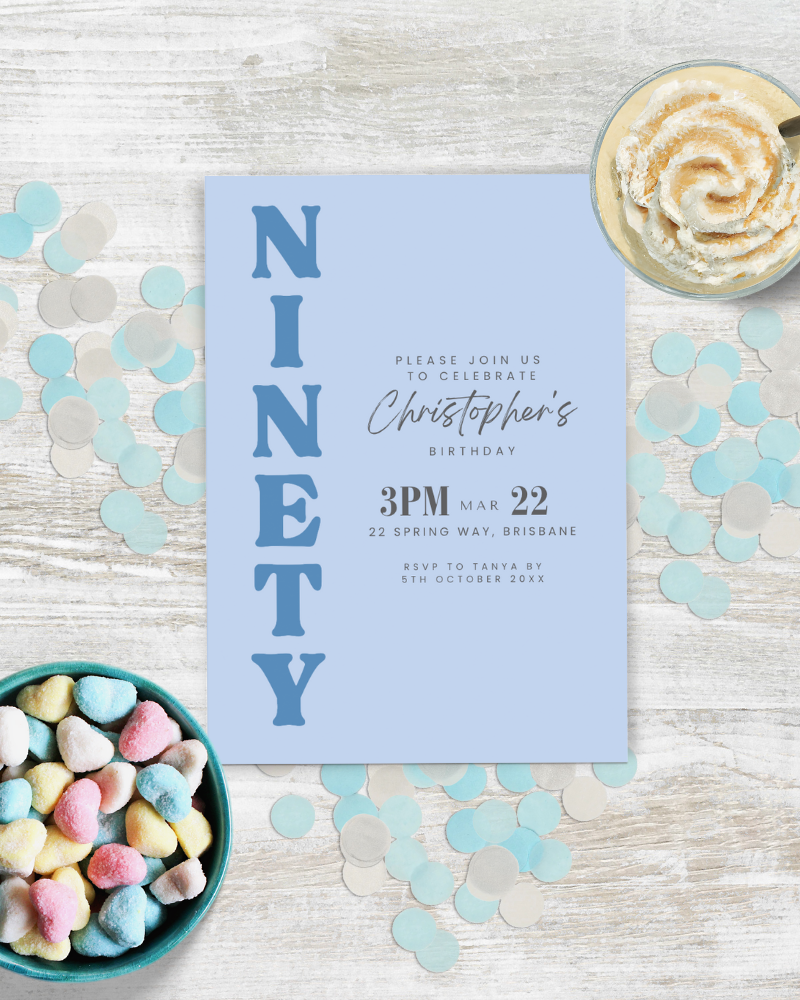 Blue invitation card for a birthday celebration, surrounded by colorful heart-shaped candies and confetti.