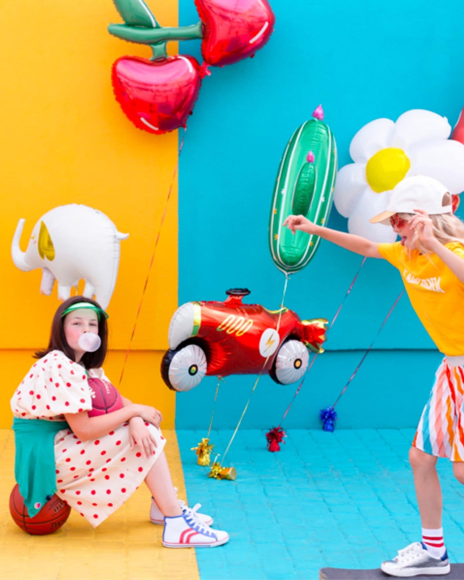 Two children play joyfully with colorful balloons in a vibrant setting, showcasing a fun and whimsical atmosphere.