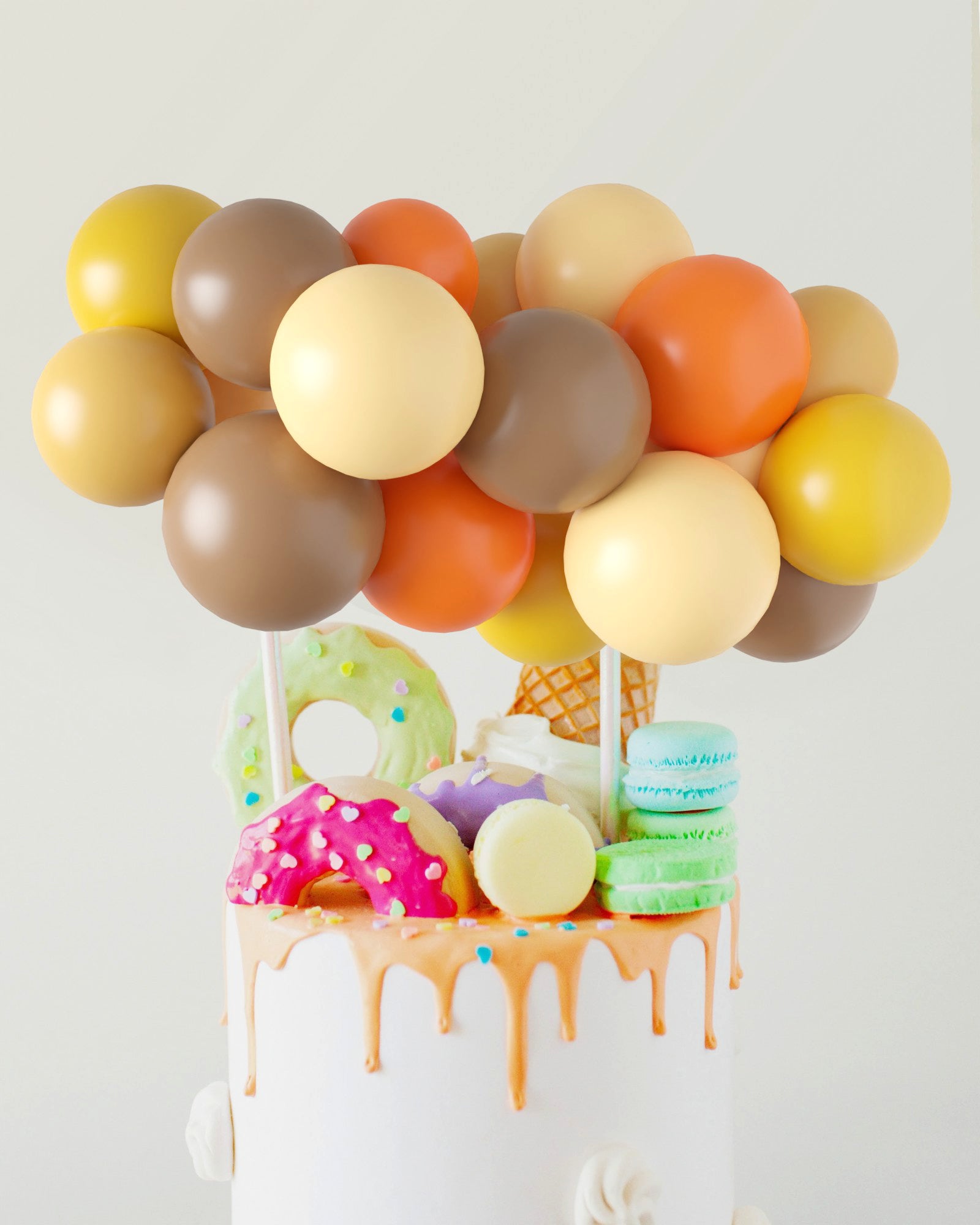 Colorful balloons in autumn hues atop a cake adorned with playful sweets and dripping icing.