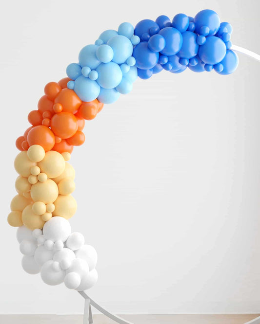 Colorful balloon garland in shades of blue, orange, yellow, and white, elegantly arching against a light background.