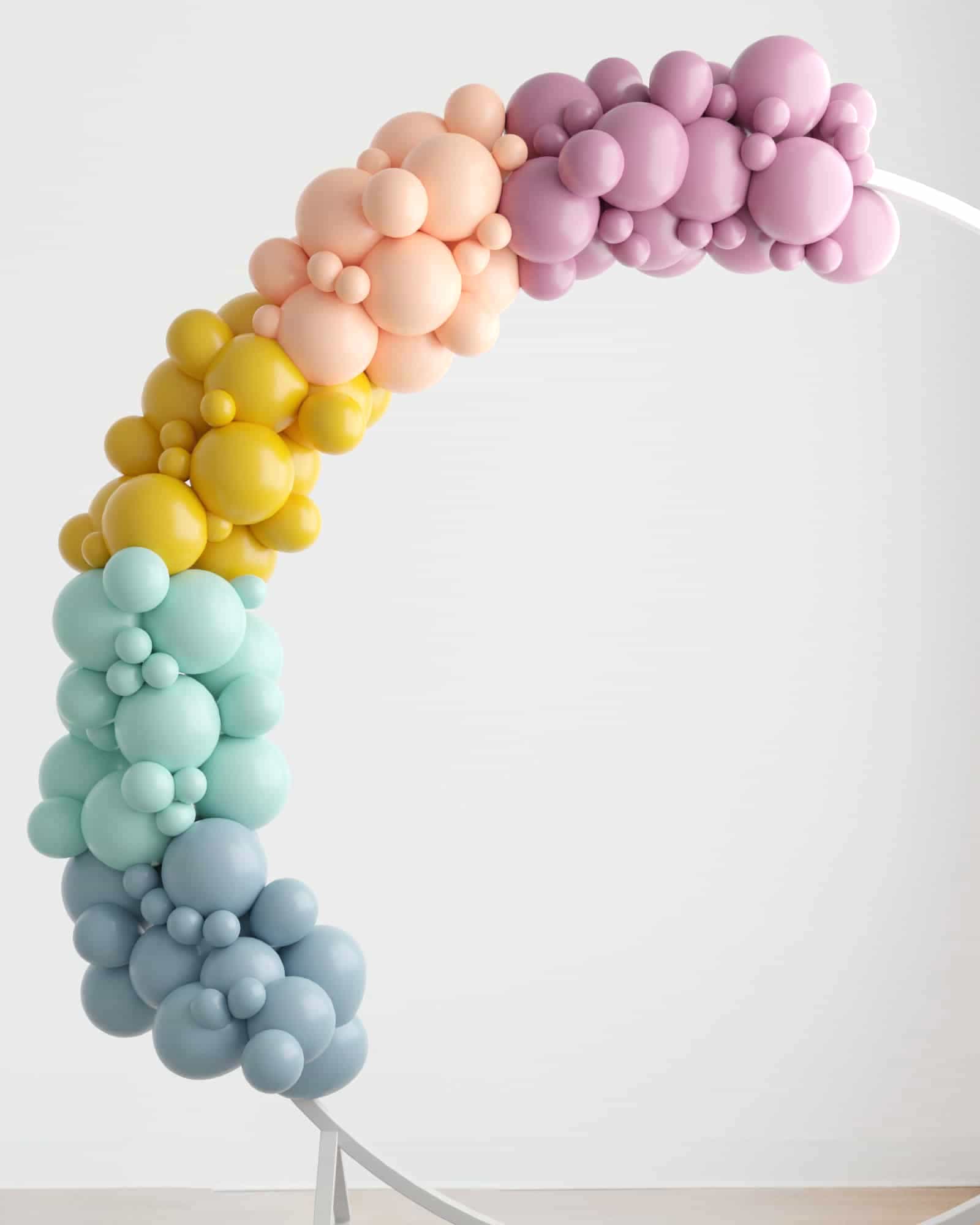 A colorful balloon garland features pastel shades of pink, yellow, green, and blue, creating a whimsical arch.