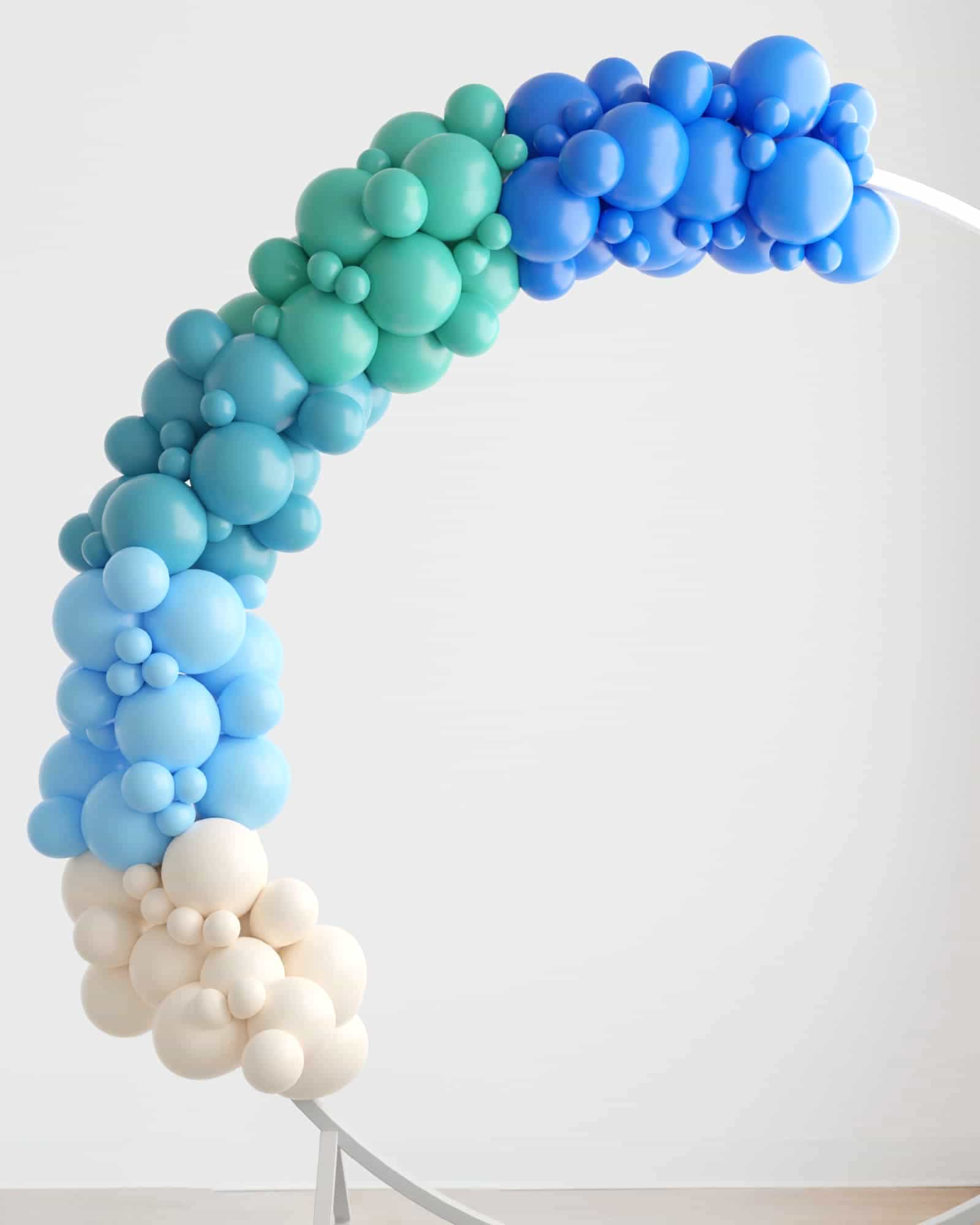 A colorful garland of varying-sized balloons in shades of blue and green, elegantly arching against a light background.