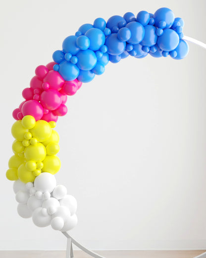 Colorful balloon garland featuring pink, blue, yellow, and white spheres, arching gracefully against a light background.