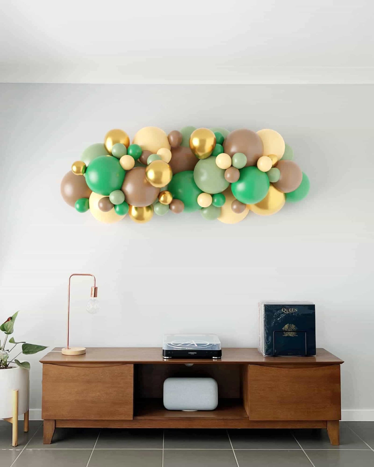 A vibrant balloon garland featuring shades of green, gold, and brown, enhancing a modern interior space.