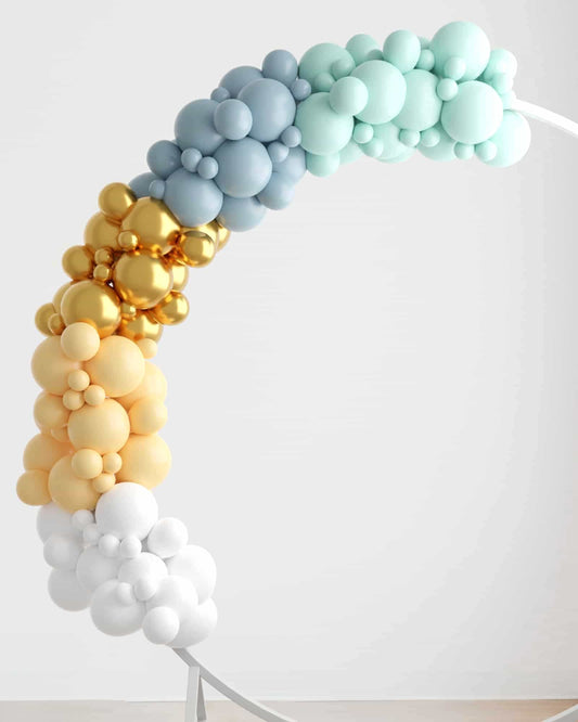 Colorful balloon garland featuring shades of blue, mint, gold, yellow, and white, elegantly arching against a light backdrop.