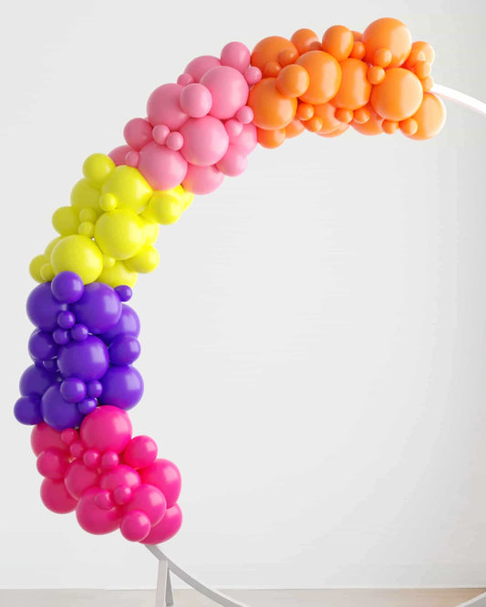 A vibrant balloon garland in a rainbow of colors, featuring clusters of pink, purple, yellow, orange, and green hues.